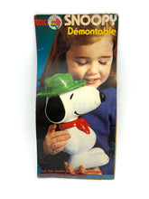 Load image into Gallery viewer, Packaging of Snoopy plush toy with child holding it.