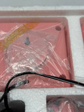 Load image into Gallery viewer, Detail of the pink device wrapped in plastic with visible cables