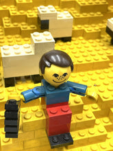 Carica l'immagine nel visualizzatore di Gallery, LEGO figure detail holding a black object with a smiling face.