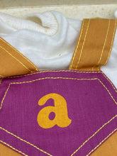 Load image into Gallery viewer, Detail of purple and yellow fabric featuring geometric pattern and letter 'a'.