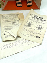 Load image into Gallery viewer, Detail of instruction papers for Ideal Toy Giggles doll in beige and brown.