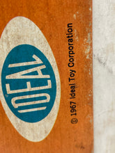 Load image into Gallery viewer, Detail close-up of the IDEAL logo on the Giggles doll packaging.