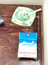 Load image into Gallery viewer, Lifestyle shot featuring a cigarette pack and green dish on a natural background.