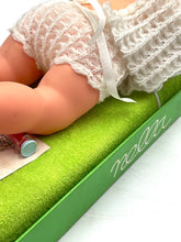 Load image into Gallery viewer, Close-up of a crocheted baby outfit featuring textured fabric and button closure.
