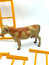Carica l'immagine nel visualizzatore di Gallery, Mattel Sunshine Family Farm detail close-up of a toy cow and fence pieces in yellow and brown.
