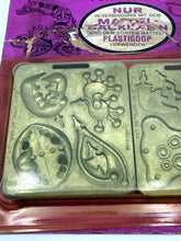 Carica l'immagine nel visualizzatore di Gallery, Close-up detail of two gold decorative stamps on the Mattel packaging.
