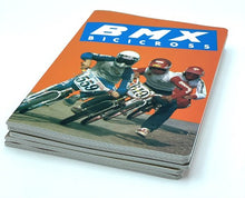 Load image into Gallery viewer, Side view of the BMX notebook with stacked magazines and action imagery.
