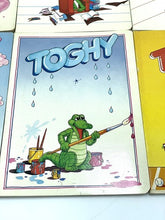 Carica l'immagine nel visualizzatore di Gallery, Detail close-up of a cartoon crocodile with a fishing rod near water.
