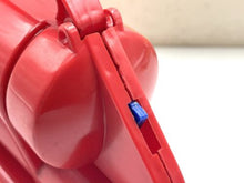 Load image into Gallery viewer, Detail close-up of a red plastic object with zipper closure and blue accent.
