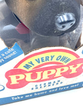 Load image into Gallery viewer, Detail of the toy puppy label featuring brand logo and colorful text.
