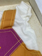 Load image into Gallery viewer, Close-up of purple and yellow fabric with geometric pattern and letter 'a'.

