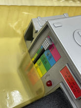 Load image into Gallery viewer, Detail view of a colorful printer cartridge featuring color labels and a red button.
