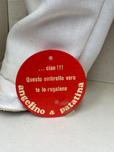 Load image into Gallery viewer, Detail of red circular tag with text on round shape against a contrasting background.
